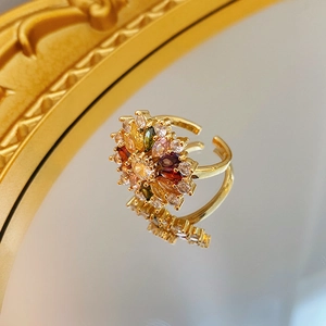 Macro shot of gold floral ring with colorful zircons on a mirrored surface