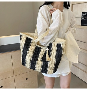 Detail of striped woven straw tote bag with black and white tassels and wooden beads
