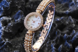 Detail of rose gold quartz watch featuring a crystal-encrusted bezel and Roman numerals