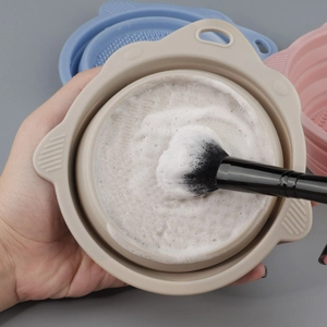 Collapsible silicone makeup brush cleaning bowl with textured bottom and beige finish