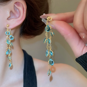 Dettaglio di orecchini lunghi a frangia placcati oro 18k con perle di vetro blu mare