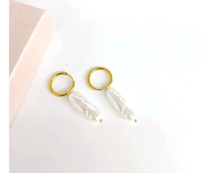 Detailed top view of C-shaped 18K gold earrings with hanging baroque pearls on white background