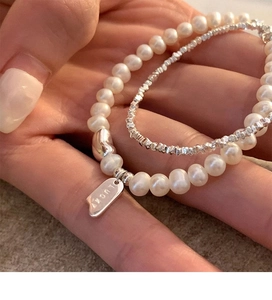 Detail showing double-layer pearl bracelet with lucky engraved square pendant and silver beads