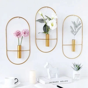 Three gold oval metal wall vases with faux plants in a Nordic minimalist home setting