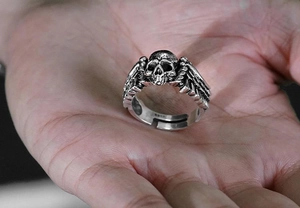Detail of silver vintage punk ring featuring a skull with wings held in hand