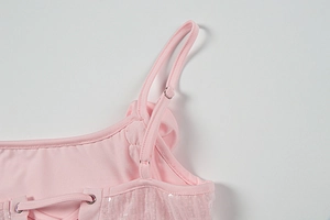 Detailaufnahme des rosa Kleides mit Pailletten-Netzstoff, Schnürung und Trägern