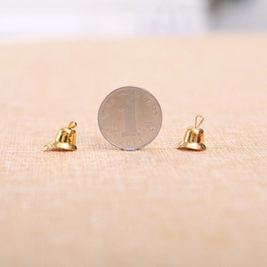 Miniature golden Christmas bells DIY hanging ornaments shown with a coin for size reference