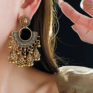 Detail of vintage gold lantern earrings with bells and tassels on model's ear