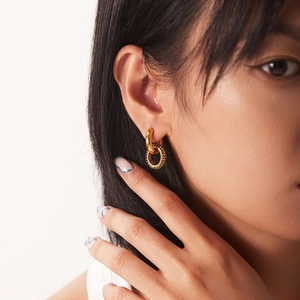Elegant gold-tone oval hoop earrings with green zircon pendants worn by a model