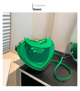 Detail einer grünen herzförmigen Handtasche mit geprägtem Muster und Goldbeschlägen