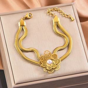 Macro shot of double-layer snake chain bracelet with golden flower and pearl on silk