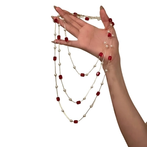 Elegant beaded long necklace featuring red crystal cubes and white pearls on hand