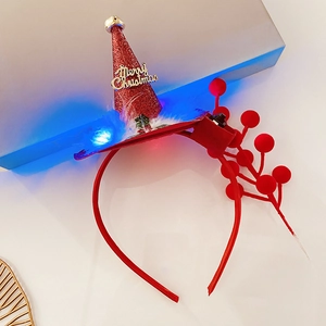 Detail of red glitter Christmas hat headband with gold bell and glowing blue LED light