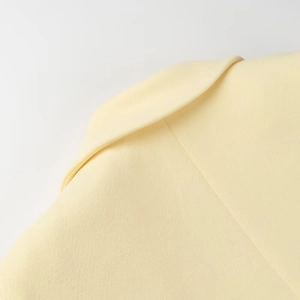 Detail of yellow wool coat lapel showing high-quality stitching and fabric texture