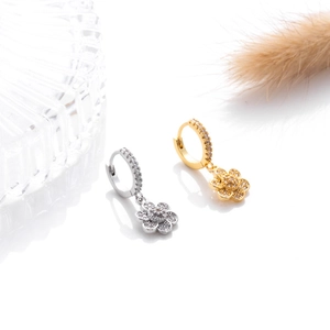 Detail of flower shaped earrings in gold and silver finish with sparkling zircon stones