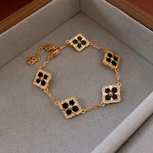 Close-up of 14K gold plated clover bracelet with black clover charms in a jewelry box