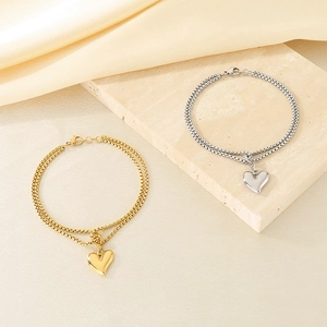 Detailed shot of double-layered gold and silver heart bracelets on silk fabric