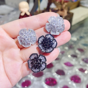 Detailed view of camellia flower earrings with sparkling zircons in silver and black colors
