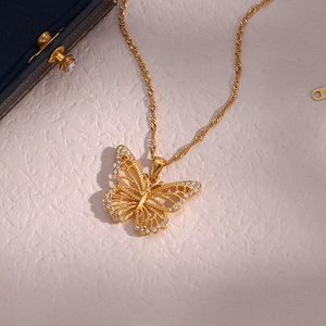 Detail of a hollow butterfly pendant with zircons on a gold-plated twisted chain necklace