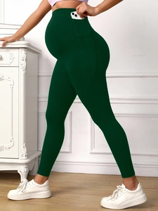 Detail view of dark green maternity yoga pants with high waist belly support and pockets