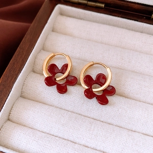 Détail macro de boucles d'oreilles pendentif fleur rouge avec créoles dorées