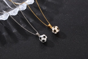 Detail of gold and silver soccer pendants with black and white enamel finish on black texture