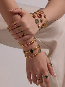 Detail of 18k gold plated bracelets with colorful faceted gemstones on a model's wrist
