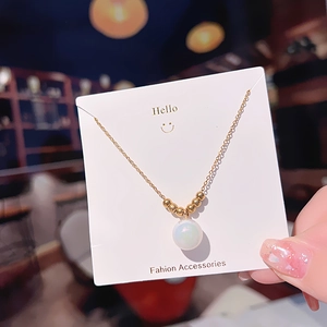 Elegant gold titanium steel necklace with iridescent pearl pendant on white card display