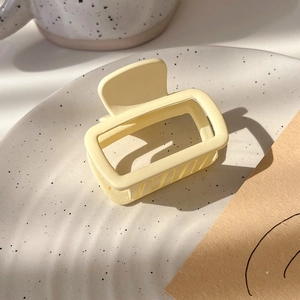Close-up of a matte cream square hair claw clip on a ceramic tray for high ponytail styles
