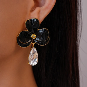 Détail de la boucle d'oreille fleur noire avec bord doré et cristal en goutte d'eau