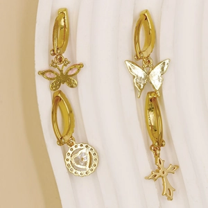 Detail of gold dangle earrings with pink zircon butterfly and cross pendants