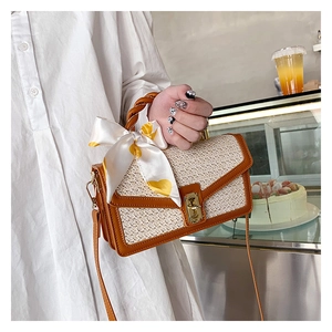 Straw handbag detail with silk scarf handle and golden twist lock in cafe setting