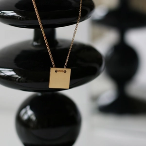 Detail of vintage square pendant with 1967 engraving on brushed 18K gold plated steel