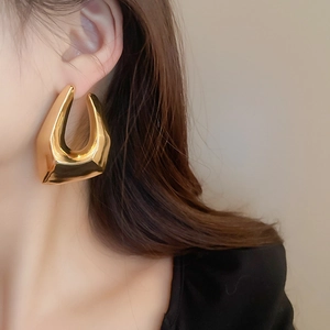 Gros plan de boucles d'oreilles géométriques irrégulières dorées portées par un mannequin
