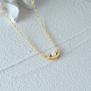 Detailed close-up of golden eye-shaped pendant with white pearl and sparkling zircons
