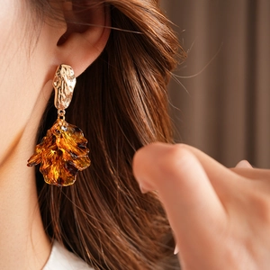 Macro detail of amber resin petal tassel earrings on model showing gold metal texture