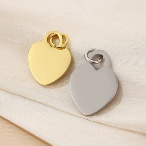 Detailed view of polished gold and silver heart pendants on silk fabric for DIY jewelry