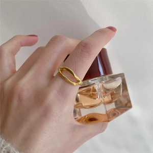 Detailed view of an irregular 925 silver cutout ring worn on finger in golden finish