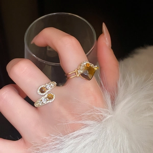 Detailed shot of gold snake-shaped open ring with brown tiger eye stones and zircons