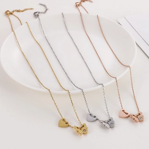 Close-up of gold, silver, and rose gold butterfly heart pendants on a white plate