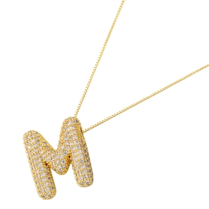Macro detail of 18K gold plated bubble letter M pendant with micro-paved cubic zirconia