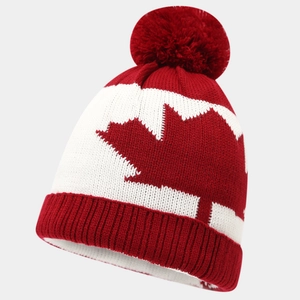 Close-up of red maple leaf jacquard knit hat with a large fluffy pom-pom detail
