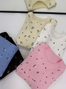 Flat lay detail showing a collection of colorful floral crewneck knit sweaters in various colors