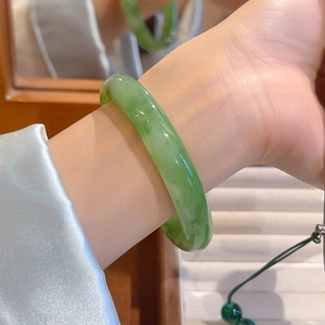Close-up of a light green resin bangle with marble texture worn on a woman wrist