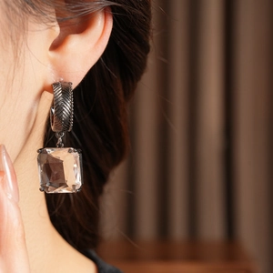 Gros plan de boucles d'oreilles en verre carré argenté avec détails gravés rétro