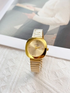 Close-up of golden square dial ladies watch with metal strap on white knit fabric