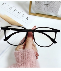Detailed view of oversized black anti-blue light glasses worn with a pink sweater