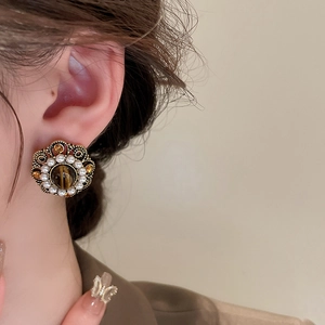 Close-up of vintage gold flower earring with tiger eye stone and small pearls