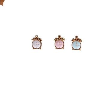 Three enamel alarm clock charms in white, pink, and blue with gold metal frames for DIY jewelry