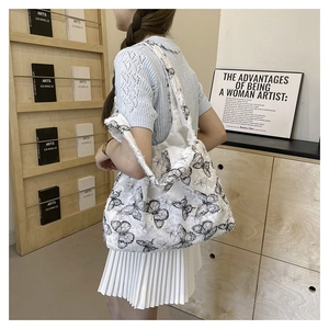 Detail of white large capacity tote bag with black butterfly embroidery on model's shoulder